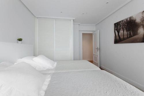 圣塞瓦斯蒂安ONDARRETA ROOM with independent entrance的白色卧室配有一张床,墙上挂着一幅画
