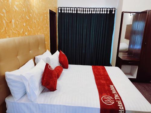 拉合尔Hotel The Holiday的一间卧室配有红色和白色枕头的床