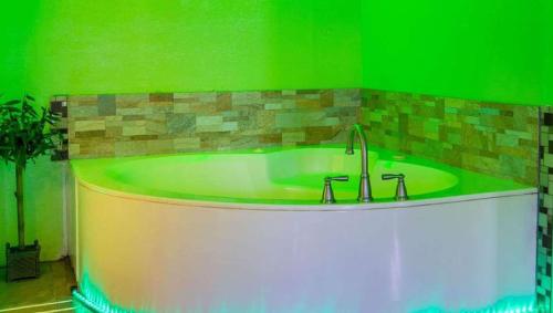 小石城Magnuson Hotel Little Rock South的绿色客房内的浴缸,配有水槽