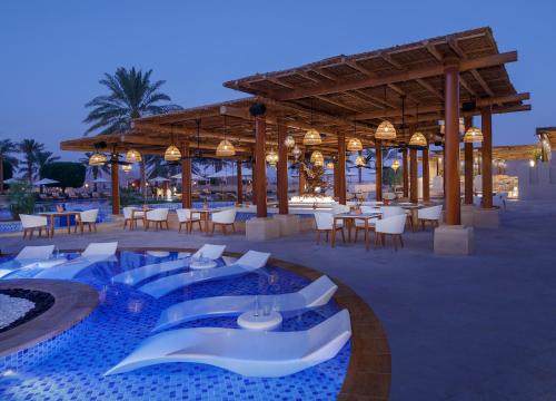 朱瑞拉盖斯尔奥萨拉安纳塔拉沙漠度假酒店的一个带游泳池和桌椅的度假酒店