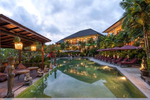 塔巴南霎哈嘉萨瓦度假别墅的度假村的游泳池,配有椅子和遮阳伞