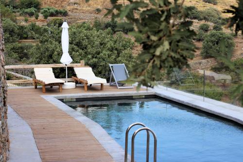 伊利达Kea Village Suites & Villas的一个带两把椅子和遮阳伞的游泳池