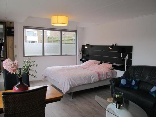 德科赫Strandhuussie Texel的一间卧室配有一张床、一张沙发和一张桌子
