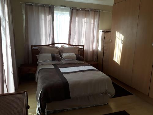 约翰内斯堡Robertsham (Halaal) Self Catering Cottages的卧室配有带枕头的床铺和窗户。