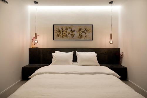 海法Urbanica Carmel- Apartments的一间卧室配有一张带白色床单的大床