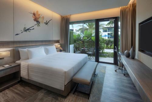 新加坡Dusit Thani Laguna Singapore的卧室配有一张白色大床和电视。