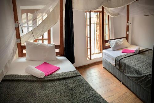 桑给巴尔Stone Town House的一间卧室配有两张床,上面有粉红色的毛巾