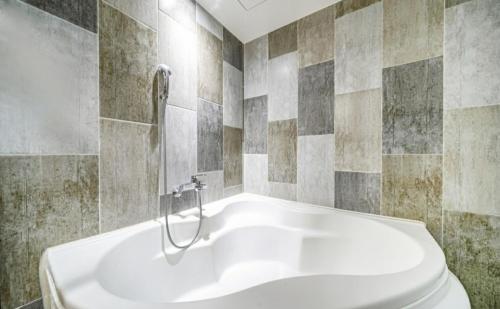 釜山五月酒店的浴室设有白色浴缸,铺着瓷砖。