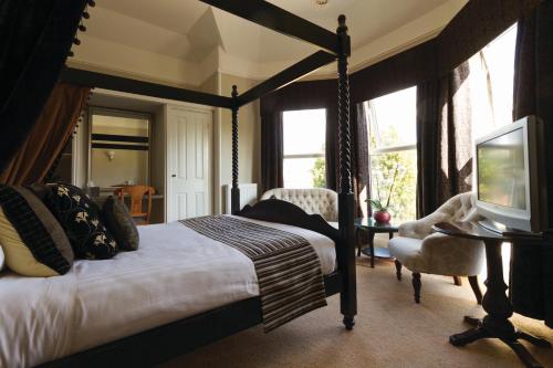 金斯林斯图尔特之家酒店的一间卧室配有一张天蓬床和一台电视机