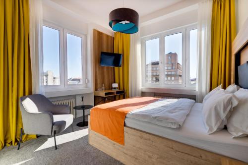 萨格勒布Bed & Breakfast Sky City Center的一间卧室配有一张床、一把椅子和窗户。