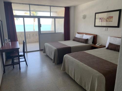 韦拉克鲁斯皇家酒店的酒店客房设有两张床、一张书桌和一个窗户。