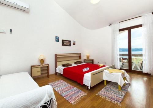 苏佩塔尔Apartments Neva - 50m to the sea的一间卧室设有红色的床和大窗户