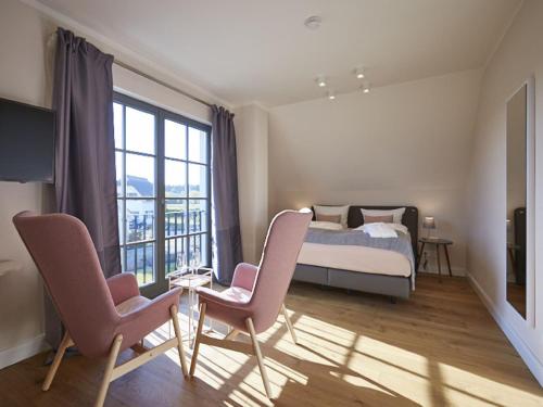 德兰斯克Reetland am Meer - Premium Reetdachvilla mit 3 Schlafzimmern, Sauna und Kamin E16的一间卧室配有一张床、两把椅子和一个窗户