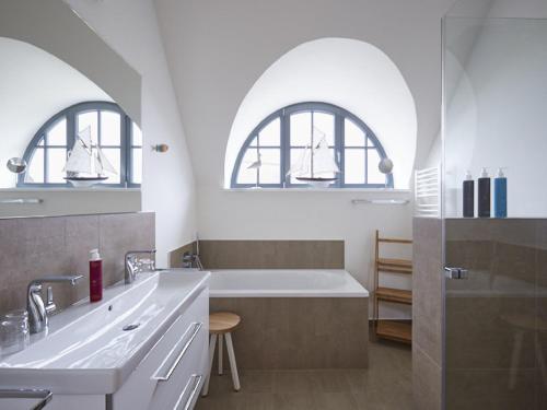 德兰斯克Reetland am Meer - Premium Reetdachvilla mit 3 Schlafzimmern, Sauna und Kamin E19的一间带两个拱形窗户和浴缸的浴室