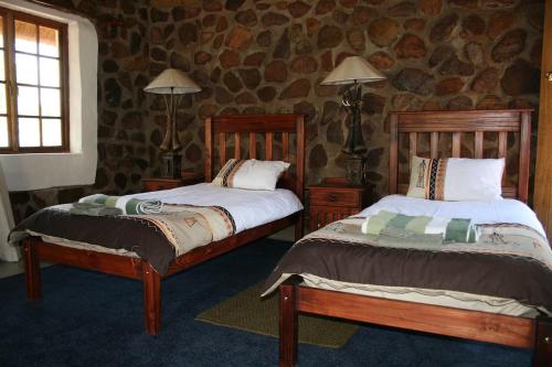 塔巴津比Griffons Bush Camp的一间卧室设有两张床和石墙