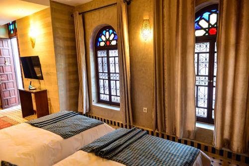 拉巴特Riad Al mazhar的一间卧室设有两张床和两个窗户。