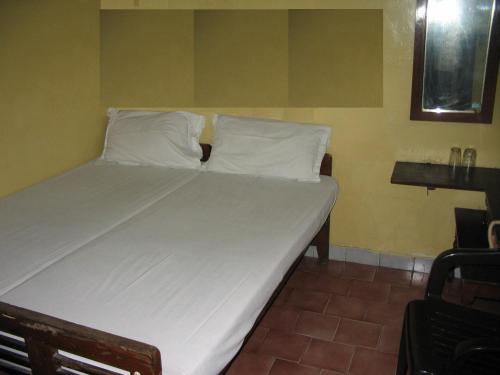 钦奈Vasantha Lodge Purasawalkam chennai的一张带白色床单和枕头的床