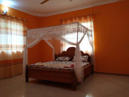 MkoaniMkoani Guest House的一间卧室配有带橙色墙壁的天蓬床