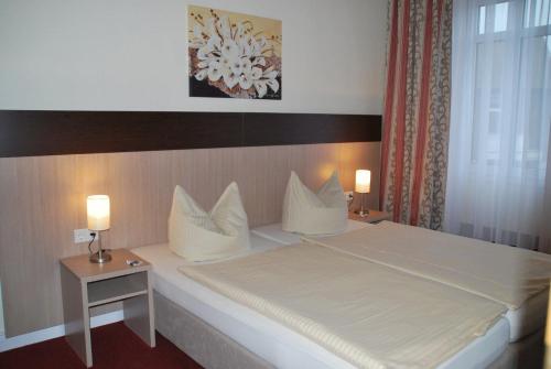 雷姆沙伊德伍珀塔尔霍夫酒店的一间卧室配有一张大床、两张桌子和两盏灯。