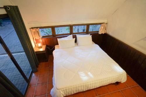 通帕蓬Baan Chai Dan的卧室配有白色的床和窗户。