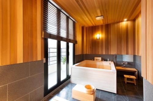 庆州Tomonoya Hotel and Ryokan Gyeongju的带浴缸的浴室,设有木墙