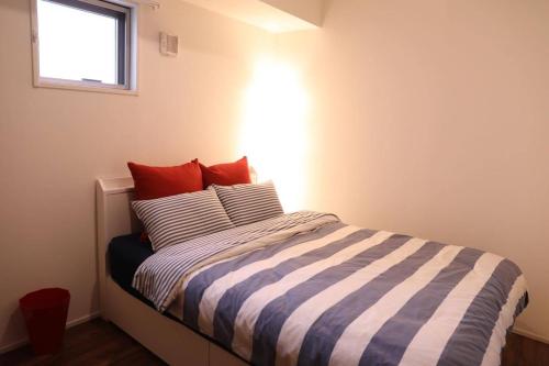 名古屋ケイアイコンホテルズ 丸の内的一间卧室配有一张带条纹床单的床和窗户。