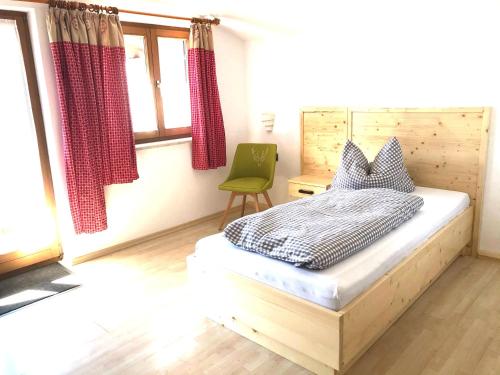 加尔米施-帕滕基兴皮科里维拉招待所的一间卧室配有一张床和一把绿色椅子