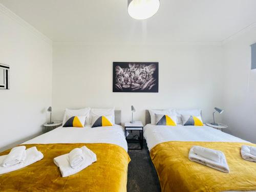 格拉斯哥Cardonald Central的黄色和白色的客房内的两张床
