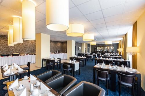 莱比锡莱比锡皇家国际酒店的用餐室配有桌椅和吊灯。