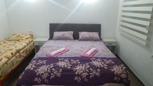 波德戈里察Apartments F的一间卧室配有带粉红色床单和粉红色拖鞋的床。