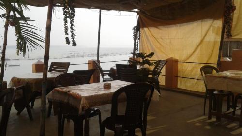 瓦拉纳西Sunrise Lodge的一间带桌椅的海景餐厅