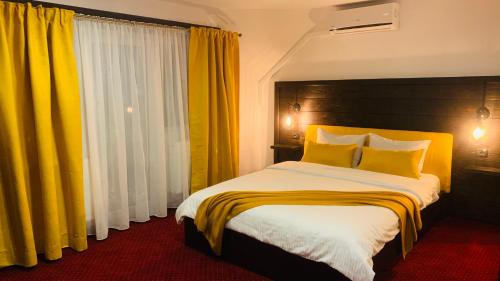 代日多姆妮卡旅馆的一间卧室配有一张带黄色窗帘的大床