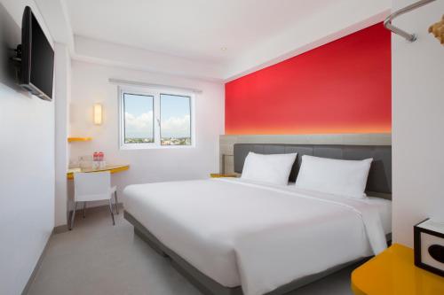 日惹日惹爱玛瑞丝马里奥波罗酒店的卧室配有白色的床和红色的墙壁