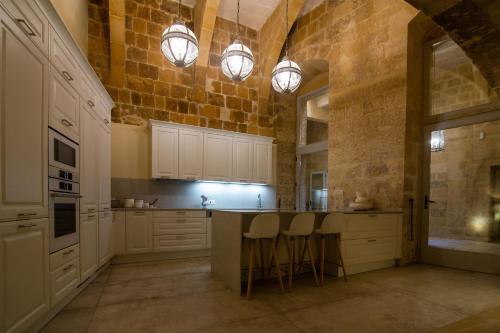 维洛里奥萨Palazzino Birgu Host Family Bed and Breakfast的厨房配有白色橱柜和石墙