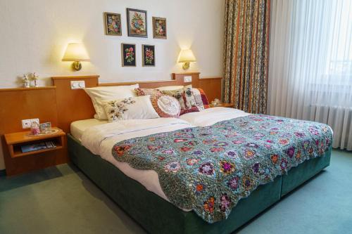 科隆Tante ALMA's Kölner Hotel的一间卧室,床上有五颜六色的被子