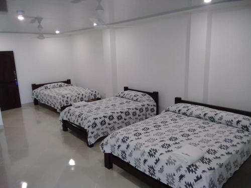 CaucasiaHOTEL TANIA的白色墙壁的客房内的三张床