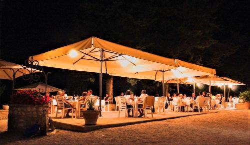 蒙特法尔科皮科洛餐饮酒店的一群人晚上坐在桌子下,在雨伞下