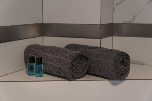 华沙Magnetic apartment Jerozolimskie A的浴室内架上的两条毛巾和两瓶