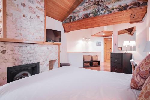 惠斯勒Rainbow by Outpost Whistler的一间卧室配有一张床和一个壁炉