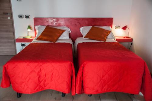 贝加莫圣露西亚住宿加早餐旅馆的宿舍间的两张床,配有红色床单和枕头