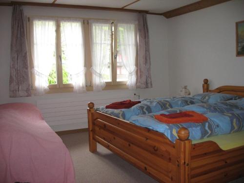 格林德尔瓦尔德斯图兹1号小木屋酒店的一间卧室配有一张带蓝色床单和窗户的床。