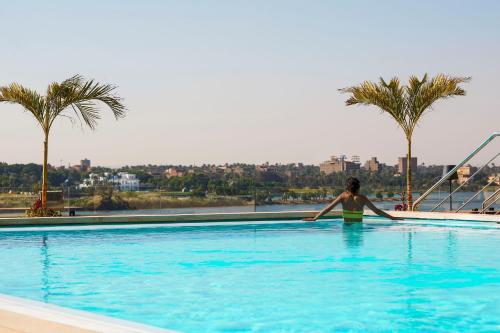 开罗Holiday Inn Cairo Maadi, an IHG Hotel的站在棕榈树游泳池中的女人