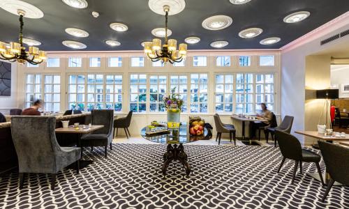 维也纳杰斯霍夫阿姆拉特斯酒店的用餐室设有桌椅和窗户。