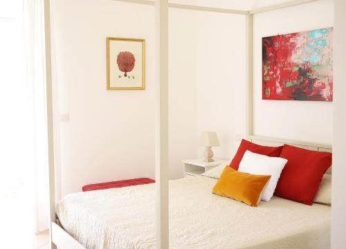 卡普里Casa Tarantino Charming apartments的白色卧室配有红色和橙色枕头的床