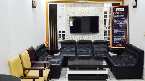 卡拉奇GOHO Rooms Badar的一间设有黑色皮椅和平面电视的等候室