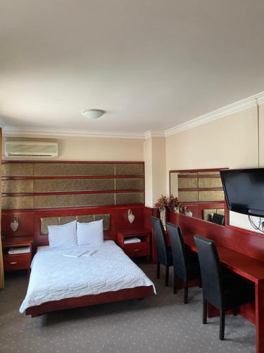 巴尼亚卢卡卡迈勒酒店的一间卧室配有一张床、一张书桌和一台电视
