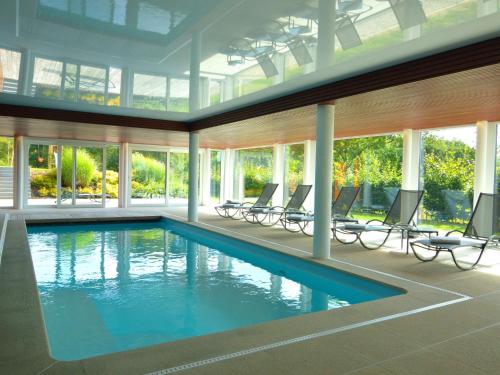 马尔梅迪Rich Holiday Home in Malmedy with Indoor Heated Pool的游泳池,带椅子和窗户