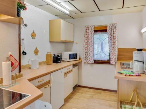 SchmogrowHoliday home in the forest的厨房配有白色橱柜和窗户。