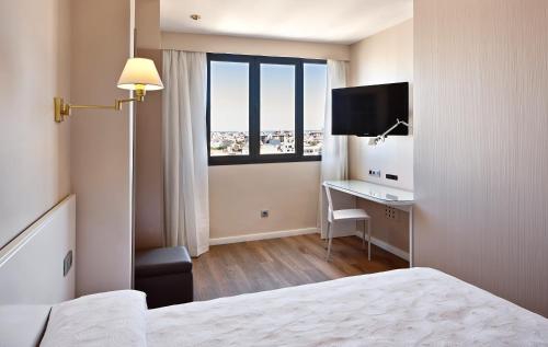 马略卡岛帕尔马守护神酒店的配有一张床、一张书桌和一扇窗户的酒店客房