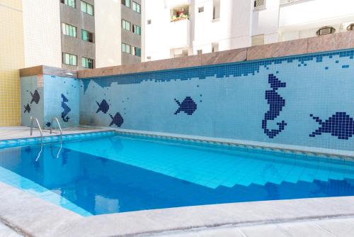 累西腓一路顺风公寓式酒店的一座建筑物边的蓝色瓷砖游泳池